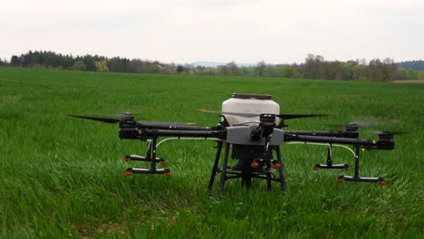 Agriculture-Drone-With-Nuzzles-Landing-in-Green-Farming-Field,-Close-Up-Slow-Motion