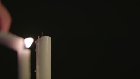 una vela blanca encendiendo dos velas blancas