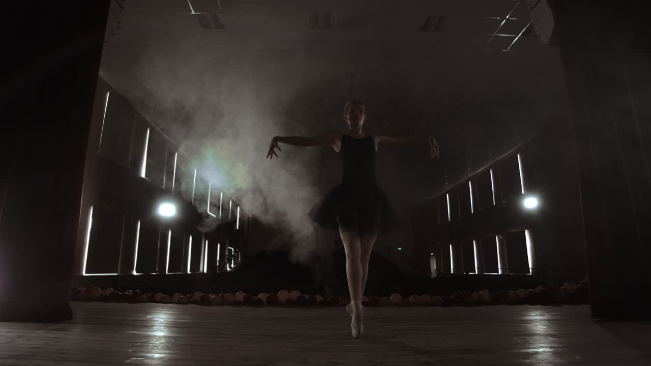 Young professional ballerina making circular movements on stage. Beautiful girl dancing in spotlights in evening during dress rehearsal