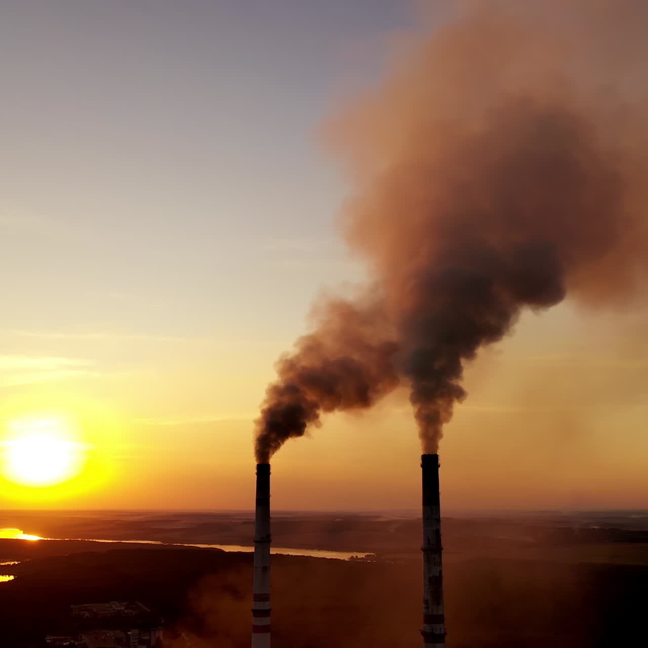 Pollution of the environment. Toxic smoke goes from industrial pipes of the factory at a beautiful sunset. Ecological disaster.