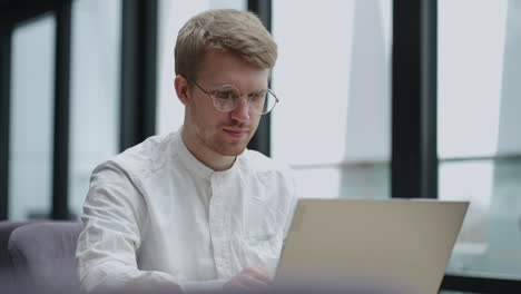 calm european man is working with laptop in office or modern coworking space portrait of handsome guy