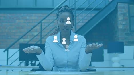 animación de iconos de usuarios de redes sociales sobre una mujer afroamericana en la oficina haciendo una llamada de video