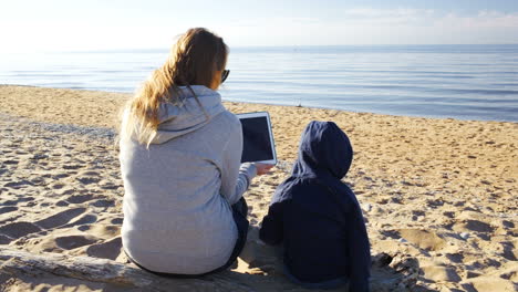 Madre-E-Hijo-En-La-Playa-Con-Tablet-Pc