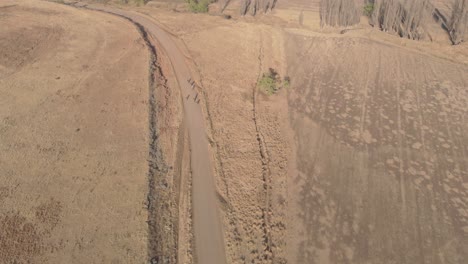 aerial shot following a group of mountain bikers racing on a gravel road