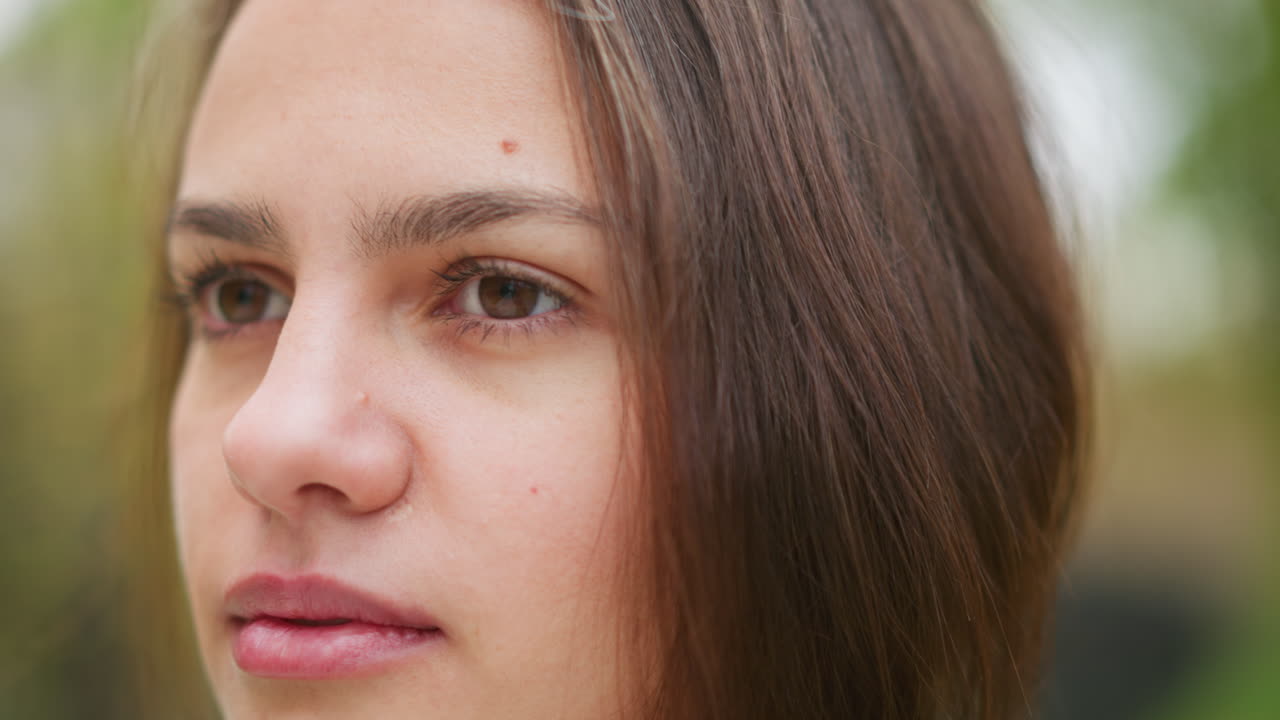 Close-up portrait view of woman blinking eyes, focused expression, natural look, casual outdoor shot, calm mood, soft gaze, beauty shot, personal moment, calmness, serenity