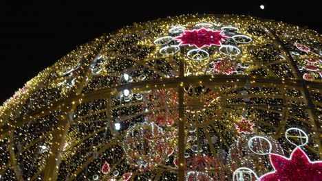 colorful christmas lights glittering all over the giant christmas ball displayed at the middle of the park - close-up shot