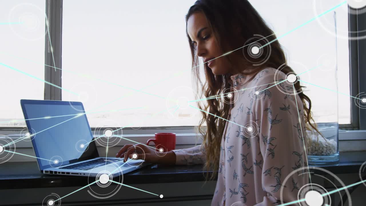 Woman placing sketch then tapping laptop, activating network overlay while organizing design notes