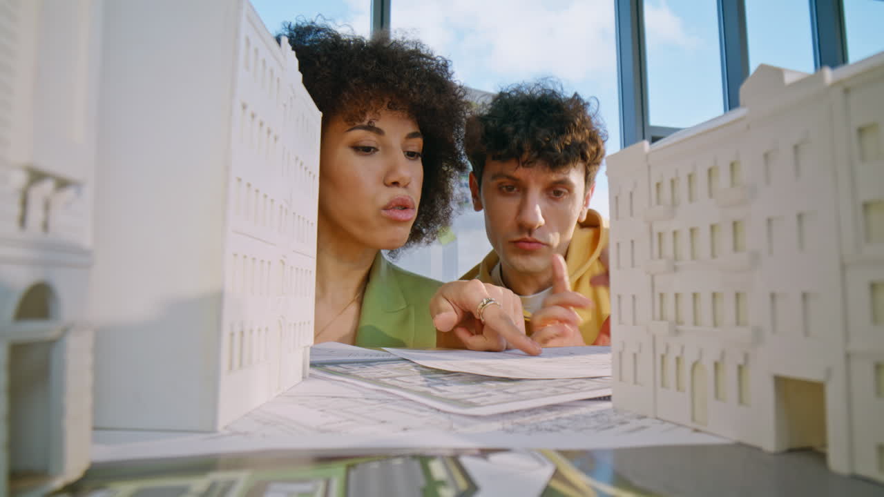 Diverse engineers discussing houses model construction view from desk closeup