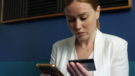 a woman with red hair making a payment using a credit card whilst shopping online