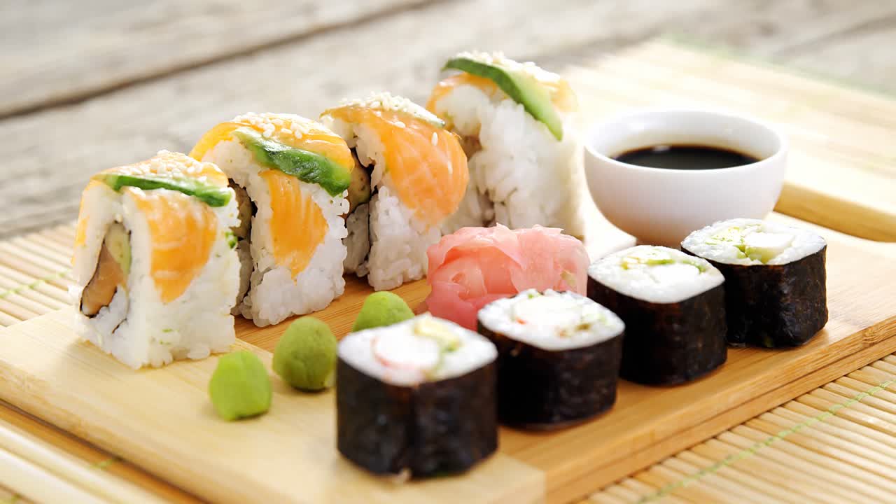 primer plano de varios sushi en bandeja con salsa