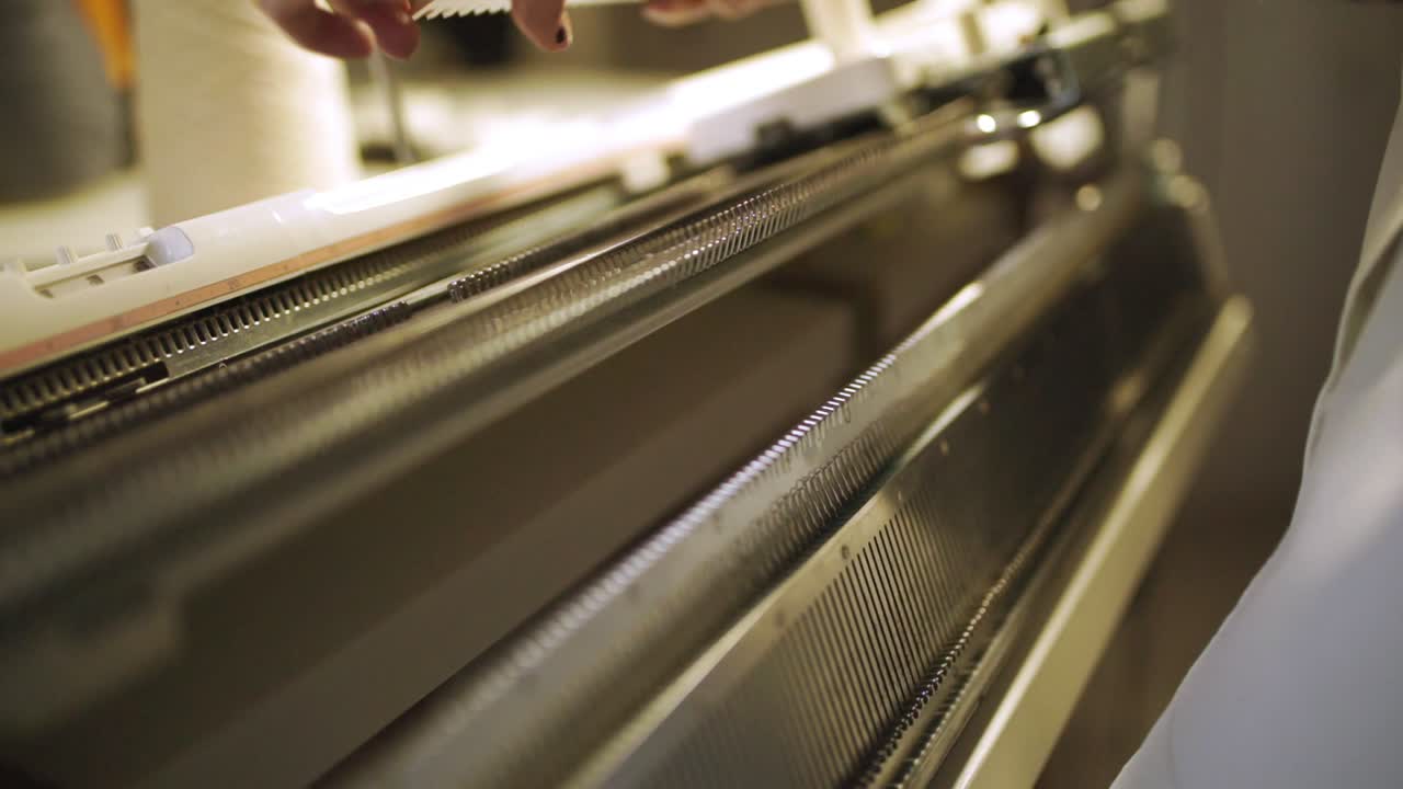 Vrouwenhanden bereiden zich voor op werk aan een weefmachine in textielwerkplaats.