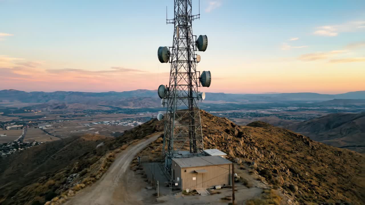 Vista aérea de una torre de telecomunicaciones en una montaña al atardecer