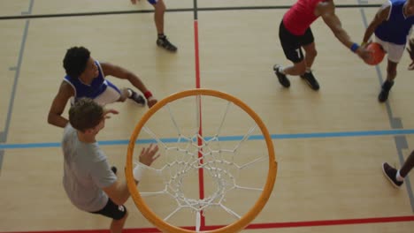 overhead view of african american male basketball player scoring goal against diverse players