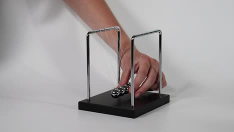 hand initiates motion of newton's cradle