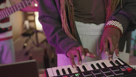 zangeres zingt en speelt synthesizer tijdens repetitie in opnamestudio met haar band 1