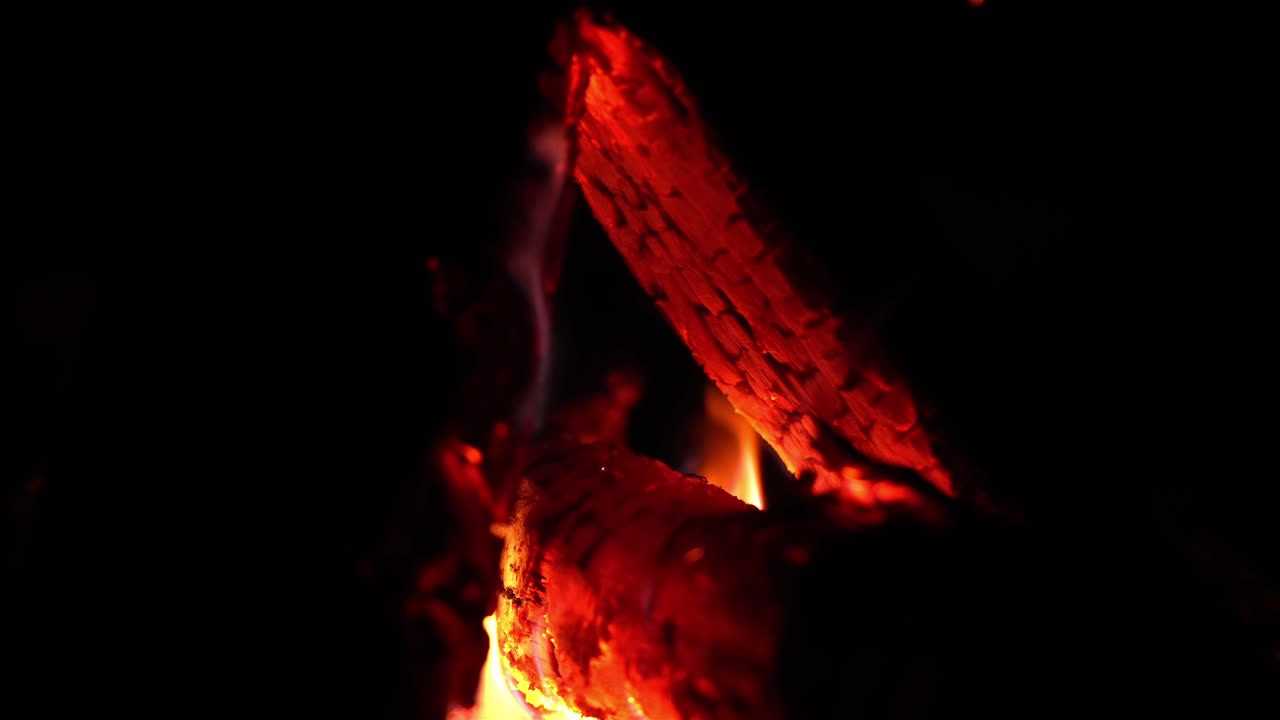 vista lateral en el fuego resplandeciente con llamas que se elevan alrededor del tronco en llamas, el humo se libera en la oscuridad