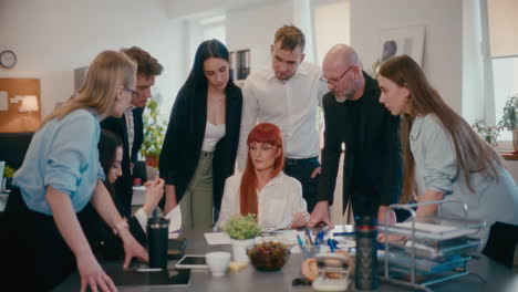 Serious-businesswoman-discussing-with-employees-in-office.