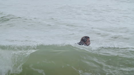 Hombre-Deportivo-En-Traje-De-Neopreno-Con-Pierna-Artificial-Acostado-En-La-Tabla-De-Surf-Y-Nadando-En-El-Océano-8