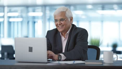 happy senior indian manager working on laptop