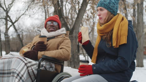 freunde genießen kaffee und essen in einem winterpark