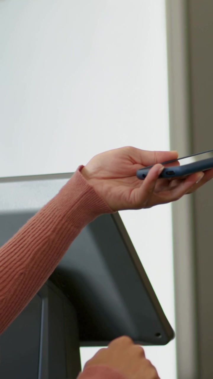 Cliente che avvicina il telefono al terminale, ruotandolo verso il lettore, mentre la visuale si allontana, sorridendo durante il pagamento
