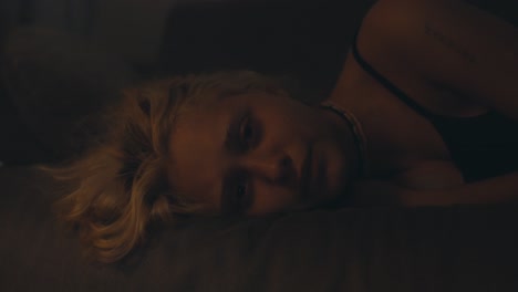 close-up portrait of a tired blonde girl in a black top lies and looks with a tired look on the couch late at night