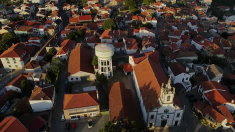 A-drone-tilts-over-a-water-tower-to-show-Belmonte-castle-as-birds-fly-by