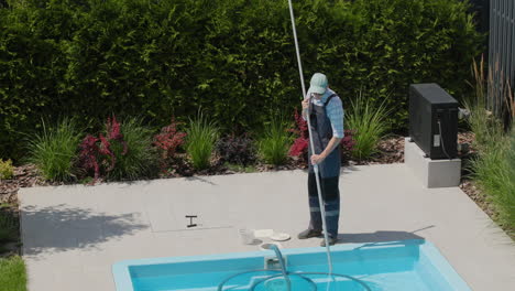 a worker cleans a swimming pool with a special vacuum cleaner. top view