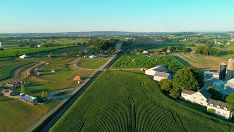steam train puffing along by amusements in amish countryside as seen by drone