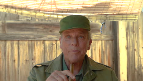 attractive elderly man talking and looking around while holding a cuban cigar