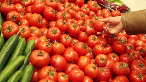 cliente seleccionando tomates en una tienda de comestibles