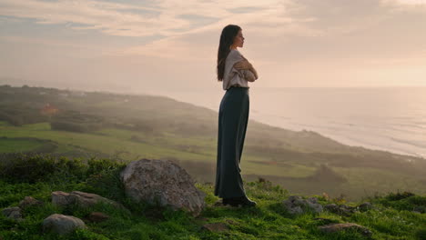 young woman standing hill looking on seascape with sunset. model posing seacoast