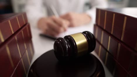 judge writes on paper at table in courtroom closeup