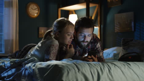 couple using smartphone in bed at night