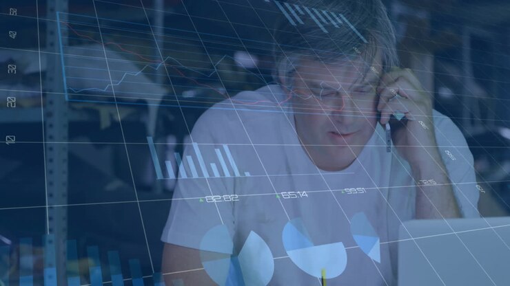 Animation of graphs, changing numbers, caucasian man talking on cellphone while working on laptop