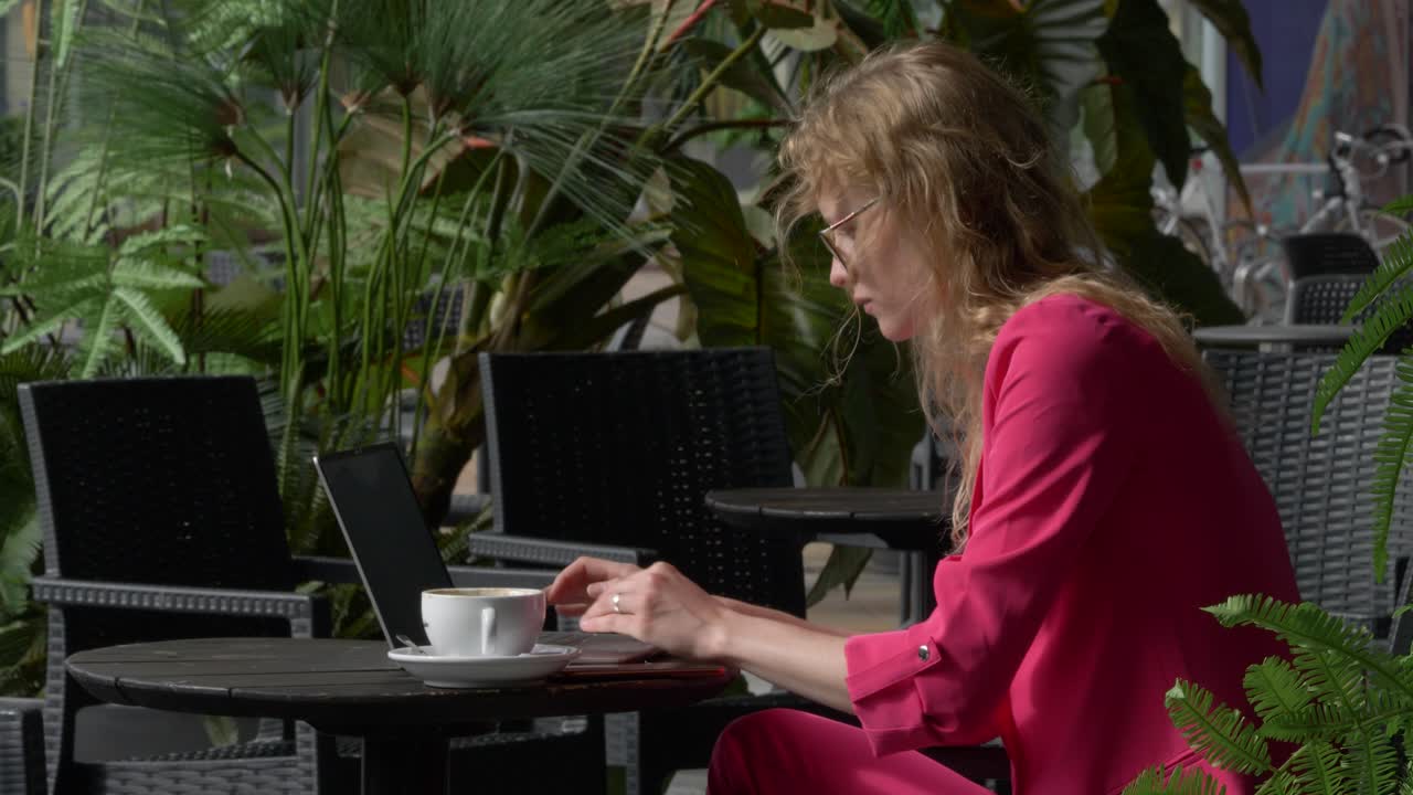 Slow motion camera shot of young stylish corporate manager working with her computer in the coffee bar