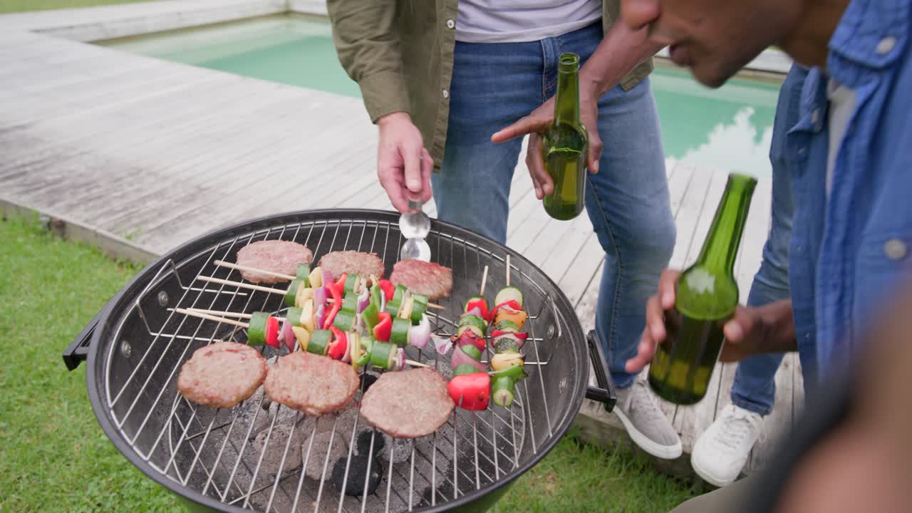 Cinco hombres posan junto a la piscina, uno de ellos con una cámara, mientras brindan, chocan sus cervezas y asan hamburguesas.