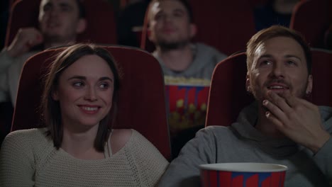 jóvenes disfrutando de una película en el cine. pareja comiendo palomitas de maíz y viendo una película