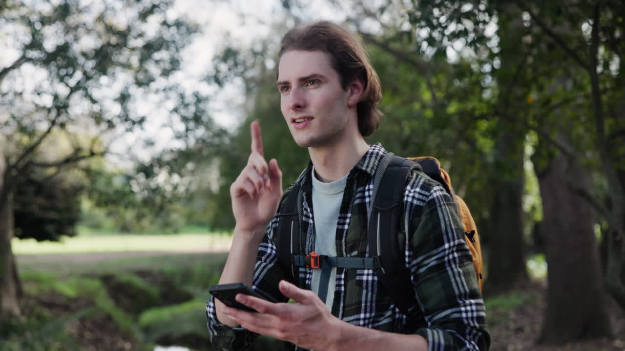Man with backpack using phone in park