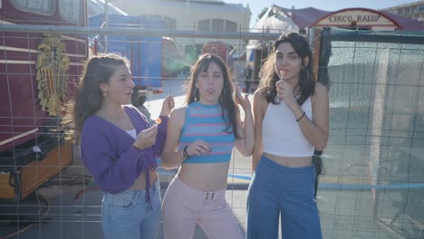 three teenage girls at a market, enjoying bubble gum