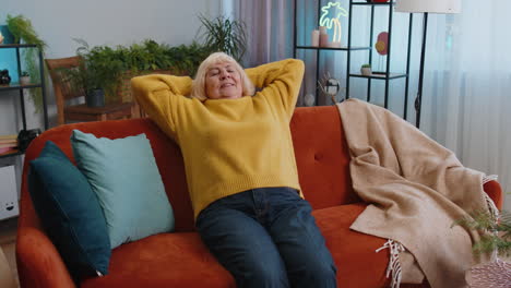 tired senior woman enjoy relaxing on home sofa resting napping after hard working day closed eyes