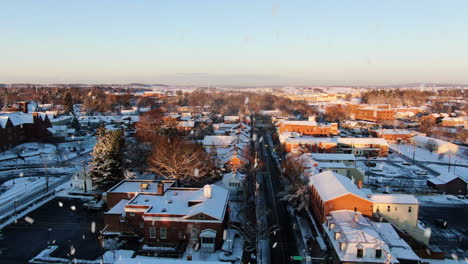 aerial dolly back downtown lititz during snowfall at sunset