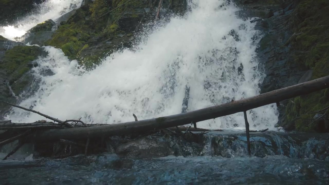 Vandfald, der falder ned ad den mosbegroede klippe i en flod.