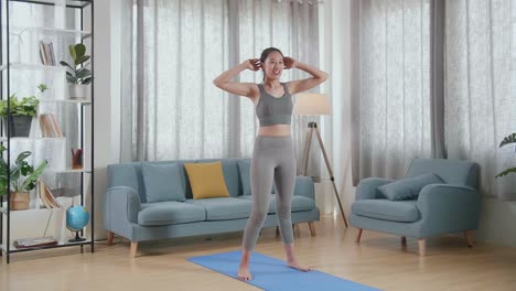 joven atleta asiática en ropa deportiva haciendo ejercicios de cardio rodillas altas y agachadas durante el entrenamiento diario en la alfombra en casa