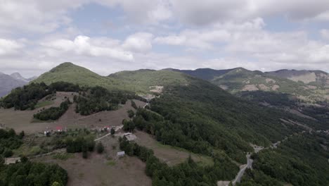 Video-Con-Un-Dron-Panorámico-Descriptivo-Que-Avanza-Por-La-Carretera-Sh20-En-El-Valle-De-Lepushë-En-Albania,-Se-Pueden-Ver-Pequeñas-Casas-De-La-Ciudad,-Cielo-Algo-Nublado