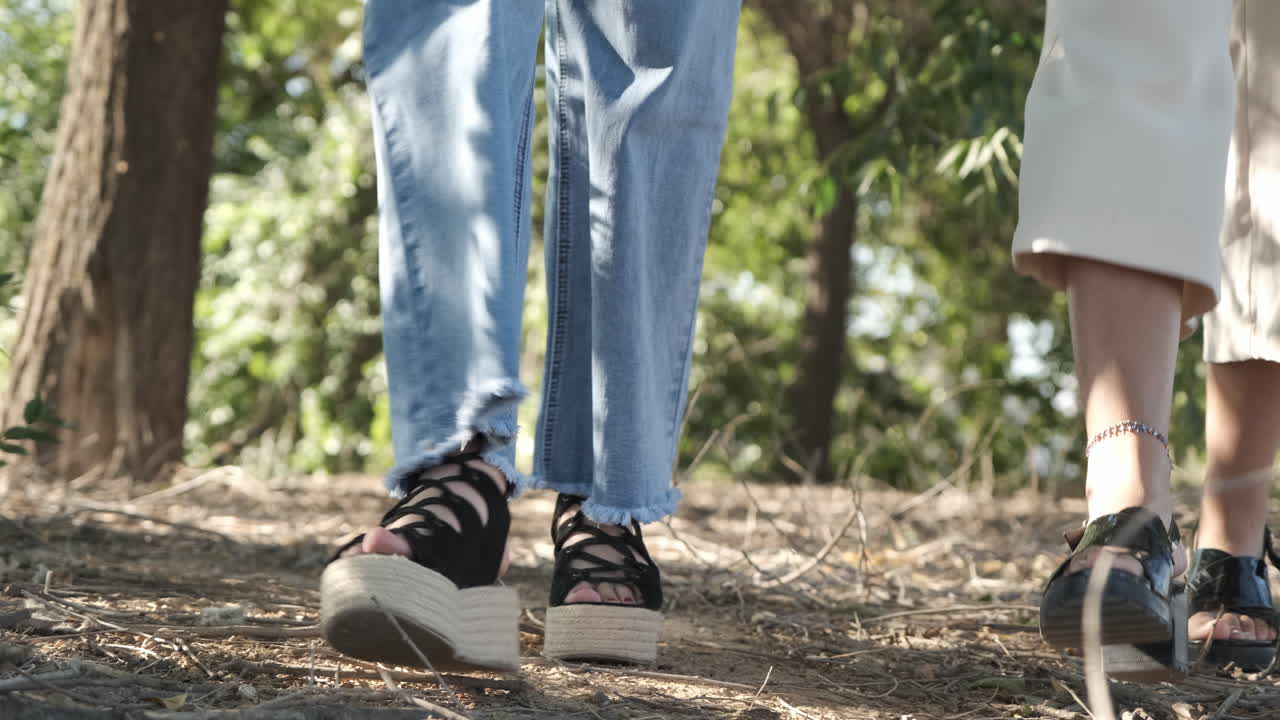 Close-up of people's feet walking on a dirt path in nature