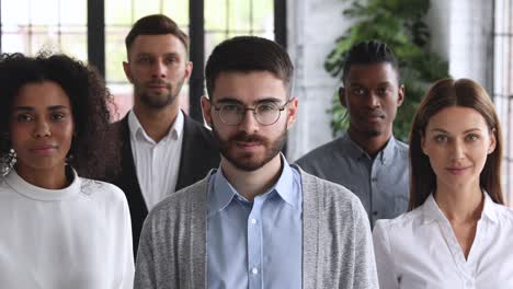 young male startup owner with business team looking at camera