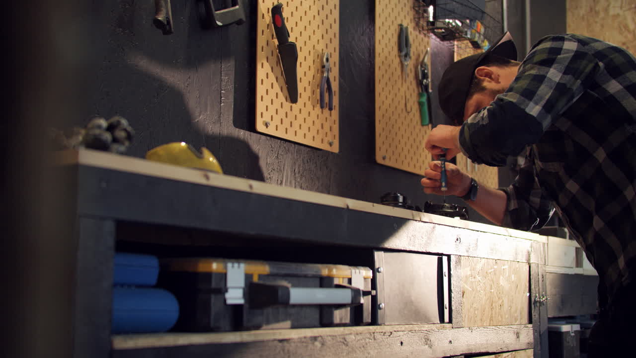 Young man by workbench diy repairing electric device