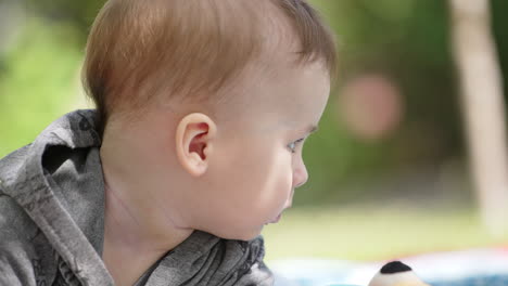 adorable caucasian baby boy outdoors in the nature. child looks aside and then into camera seriously. close up.