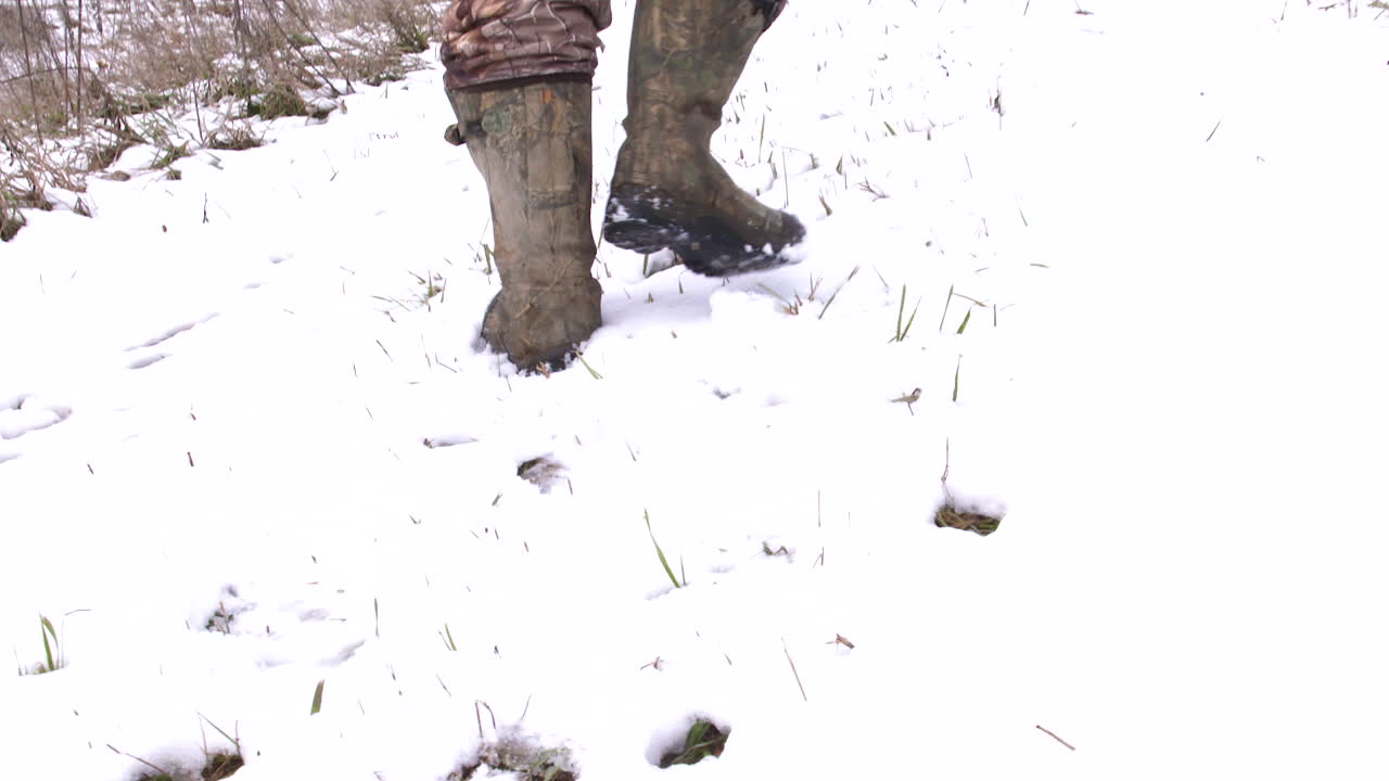 Hunter walking up snow covered hill